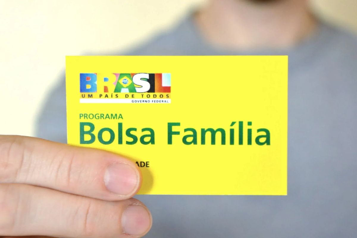 Um rapaz segurando o seu cartão do Bolsa Família após ver que o Bolsa Família pode chegar a mais de R$ 700 no mês de junho