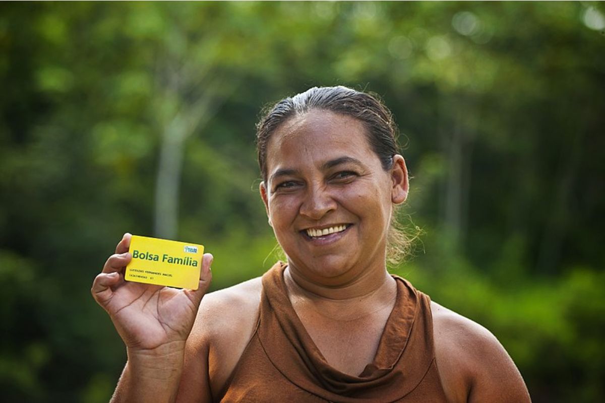 ATENÇÃO usuários do Bolsa Família: uma mulher segura o seu cartão do Bolsa Família