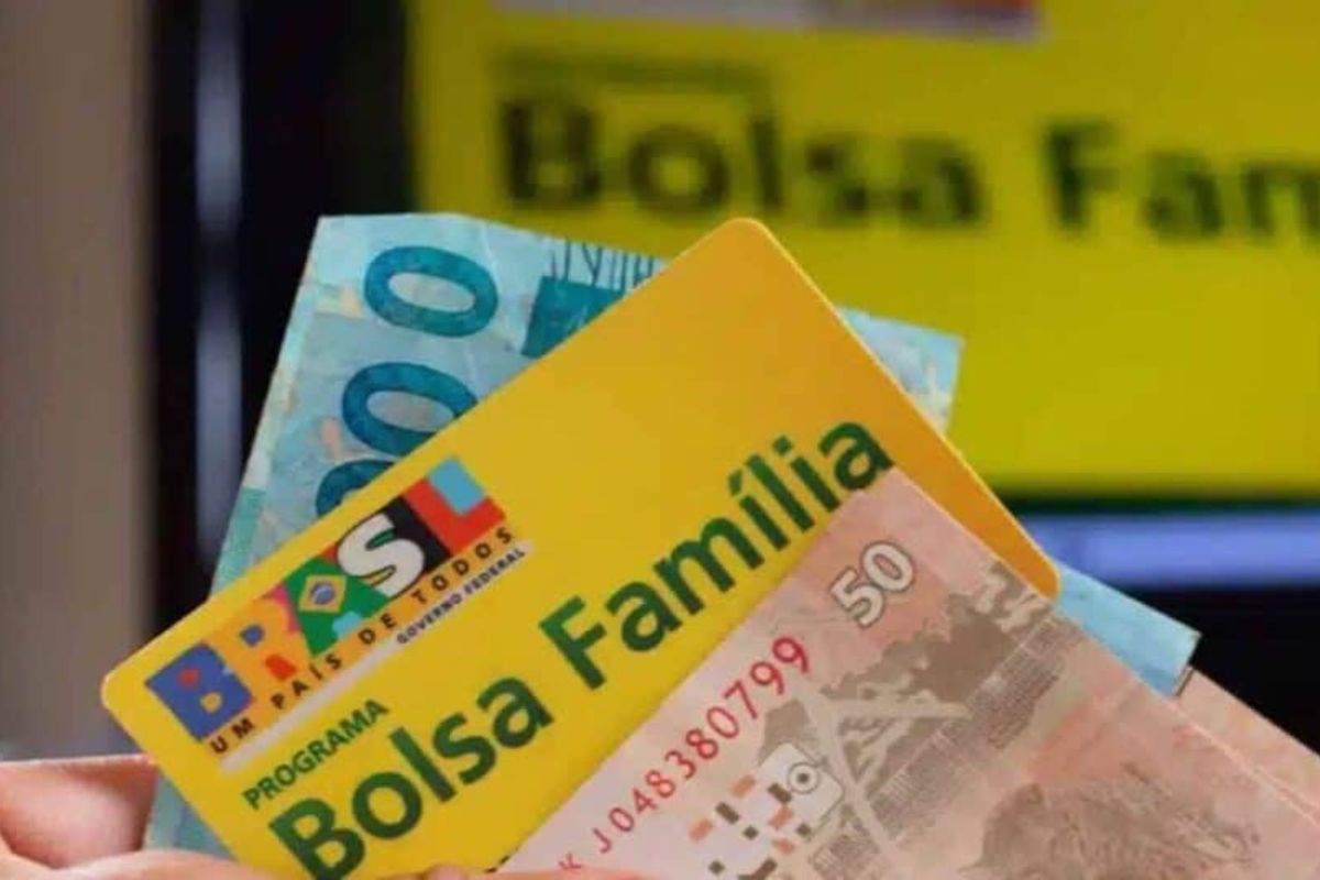 Uma pessoa segurando seu cartão entre o dinheiro após ler que o Bolsa Família atualiza com bônus de férias em julho