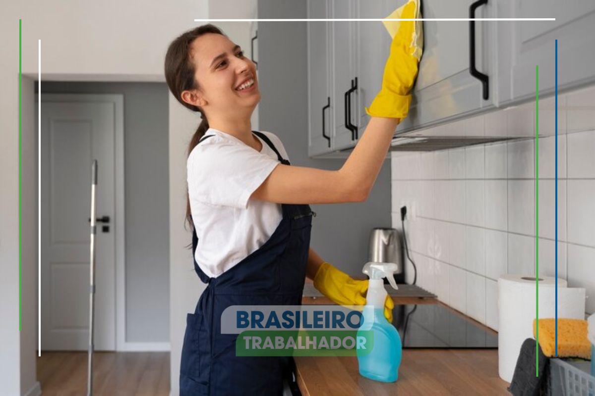 Uma mulher fazendo a limpeza da cozinha feliz após ver que domésticas e donas de casa vão receber auxílio de R$ 400 do governo