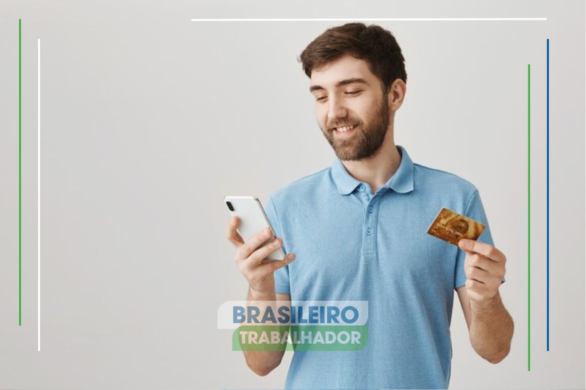 Um rapaz fazendo transferência em seu celular e segurando o cartão de crédito após ver que o Uso do PIX cresce